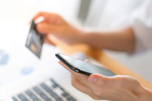Hands holding a credit card using laptop computer and mobile pho